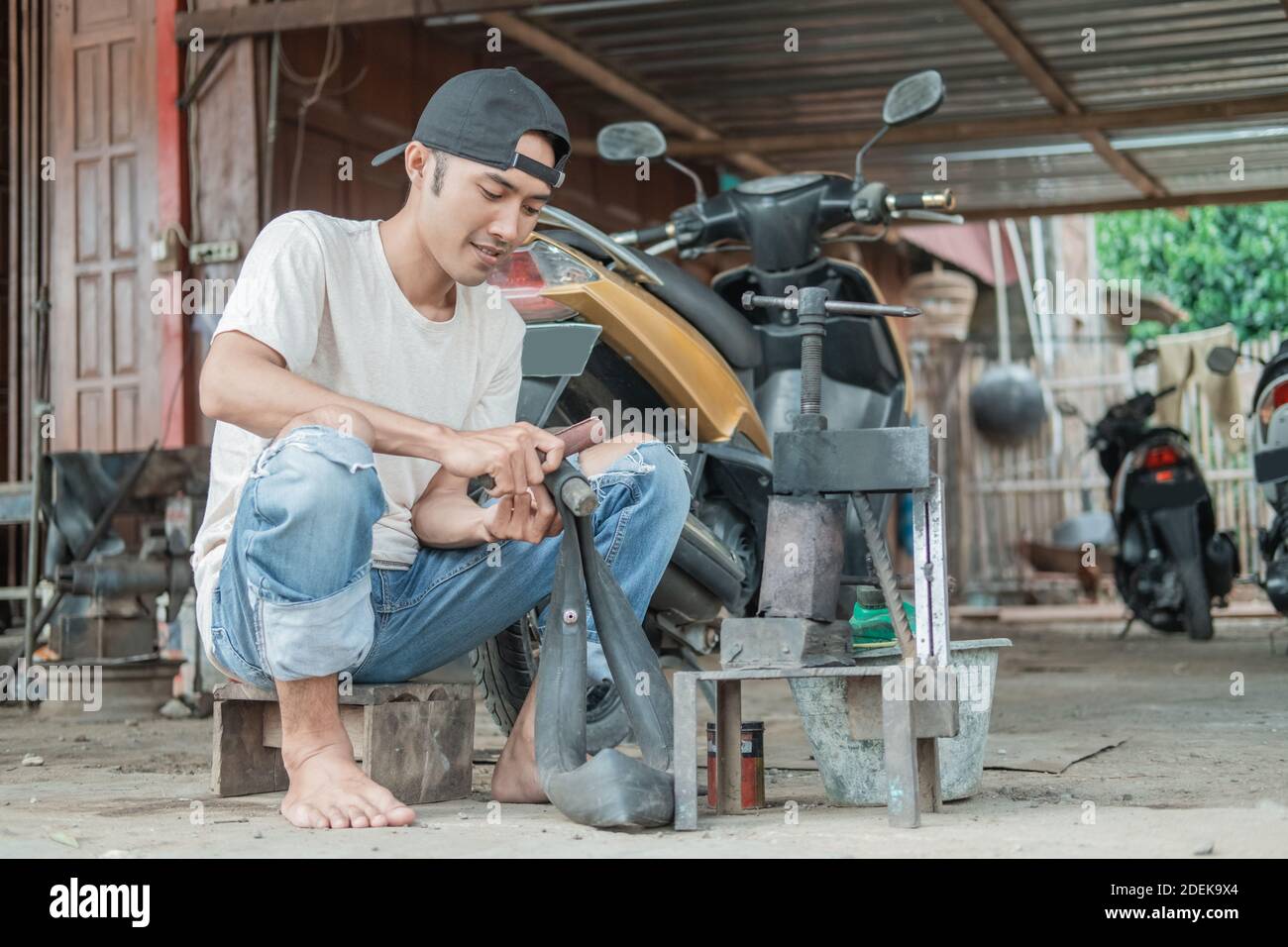 pattugliatore pneumatico seduto sfregando un tubo interno che perde in a. officina di riparazione moto Foto Stock