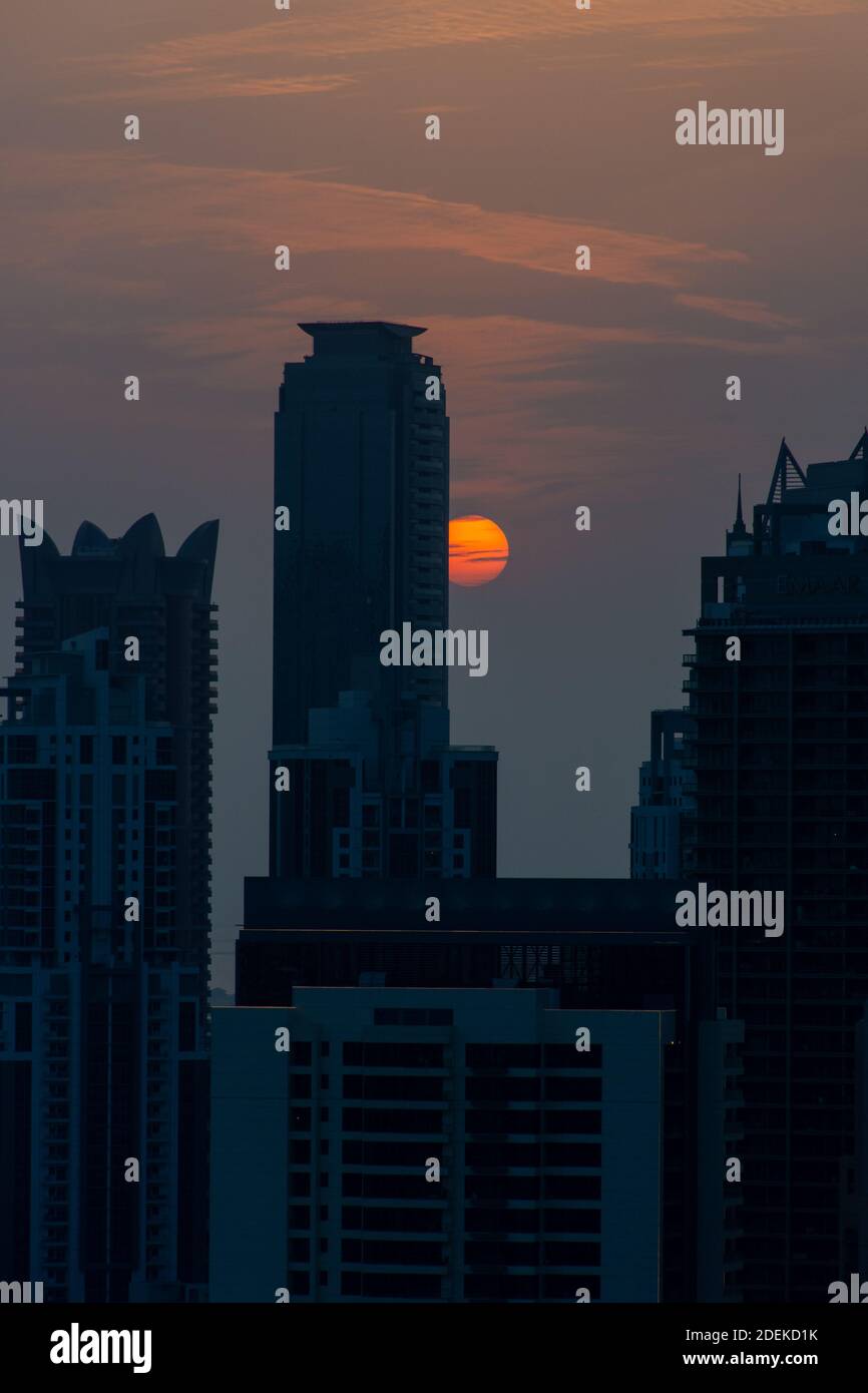 Skyline di Dubai al tramonto con cielo arancione e giallo sui grattacieli degli Emirati Arabi Uniti. (Vista verticale) Foto Stock