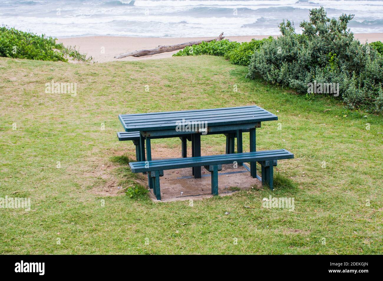 Tavolo da picnic verde su un pendio erboso che si affaccia sul mare Foto Stock