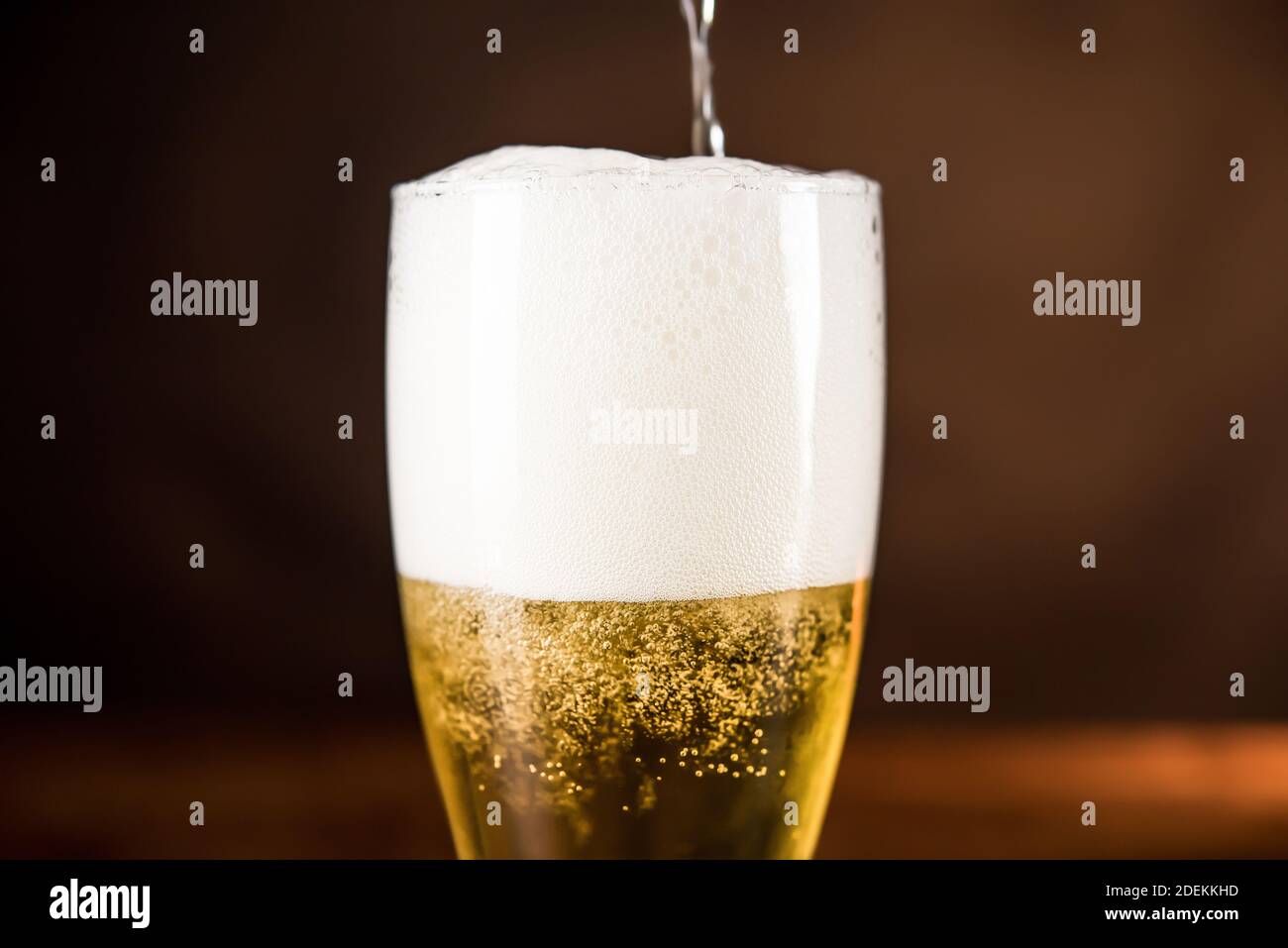 Birra fredda dorata versata nel bicchiere con schiuma schiuma Foto Stock