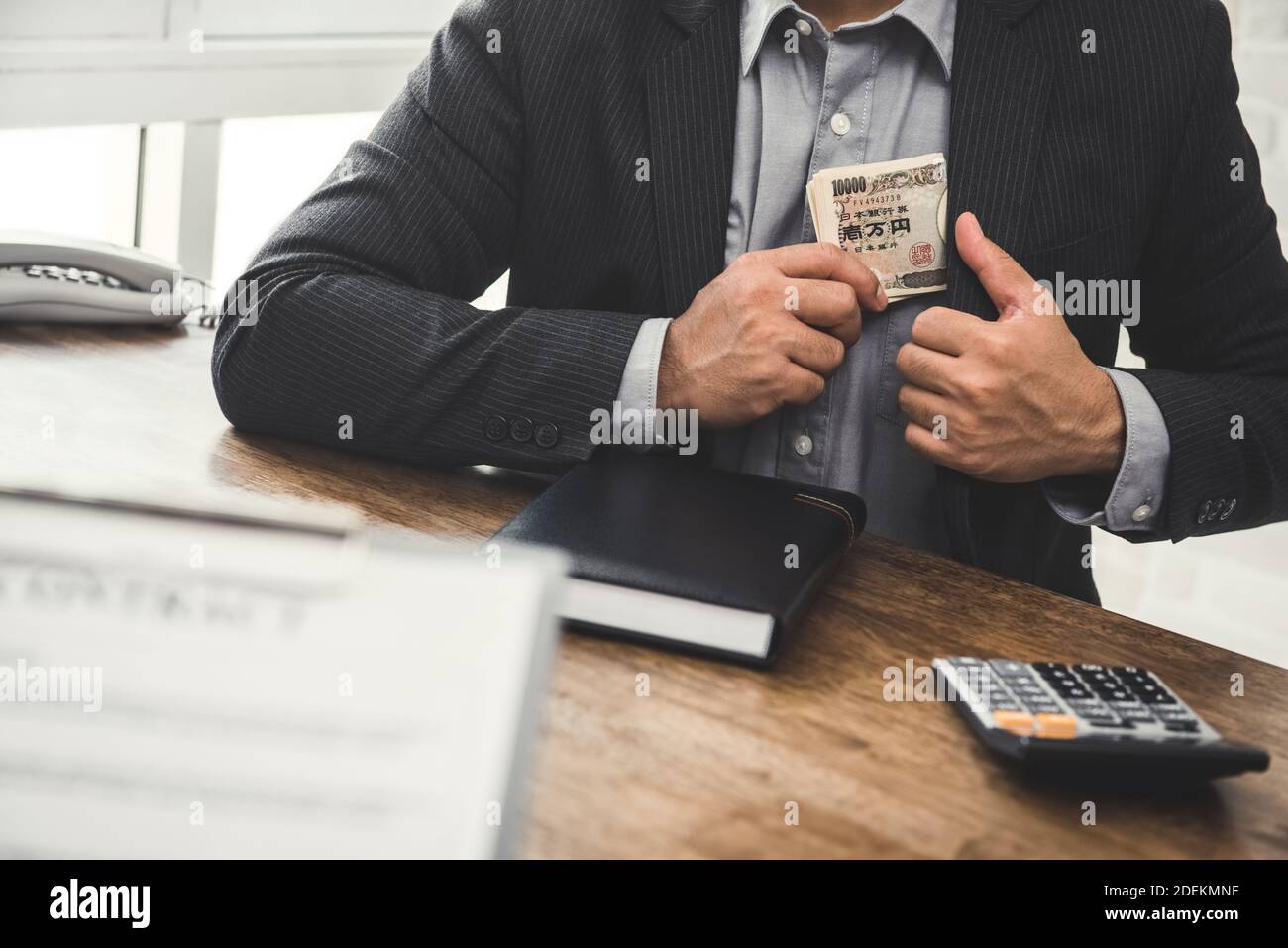 Uomo d'affari che tiene i soldi giapponesi dello yen nella tasca del vestito dopo la fabbricazione un affare in ufficio Foto Stock