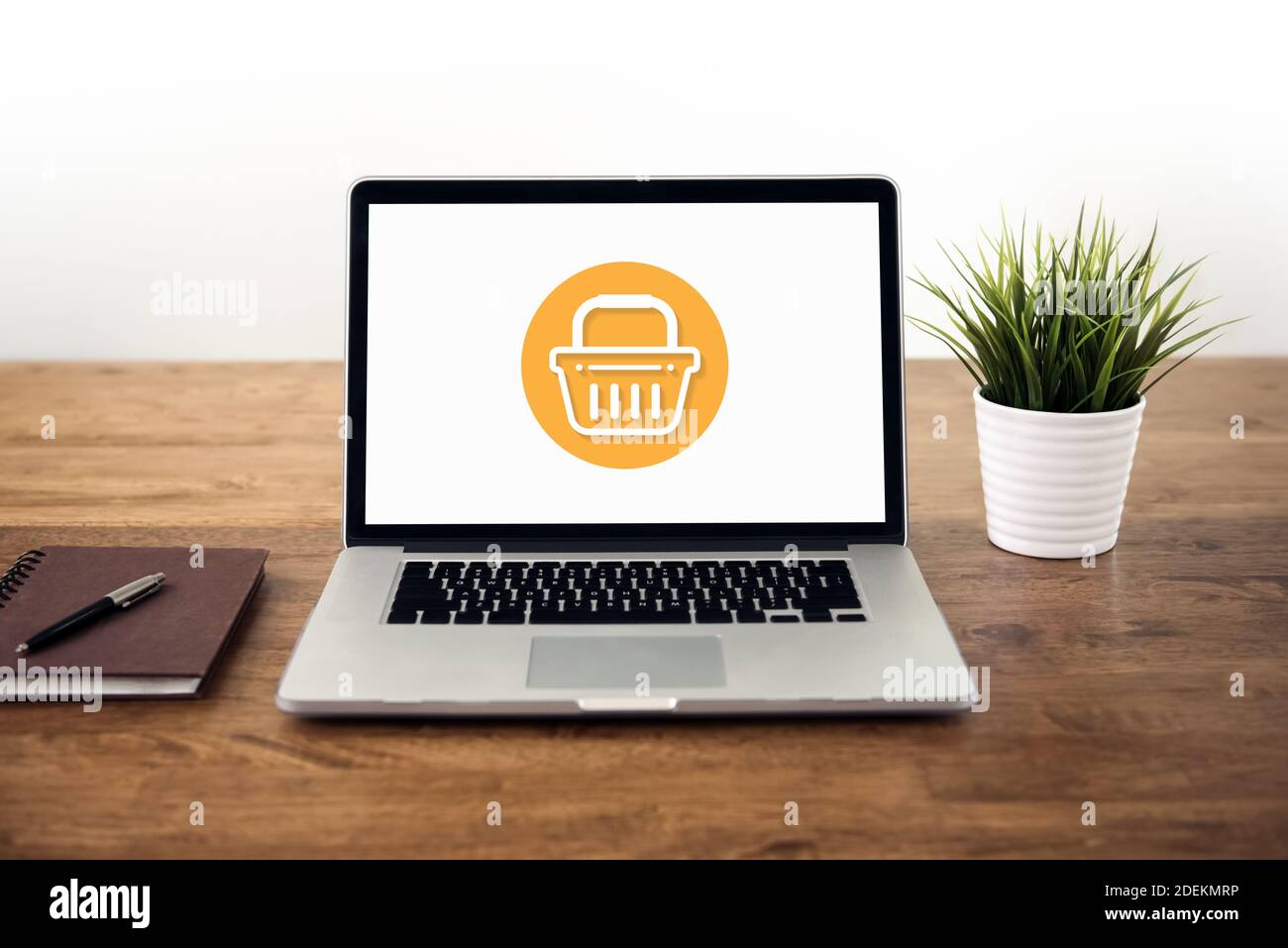 Computer portatile su tavolo di legno con icona cestino sullo schermo, online home shopping e concetti di e-commerce Foto Stock