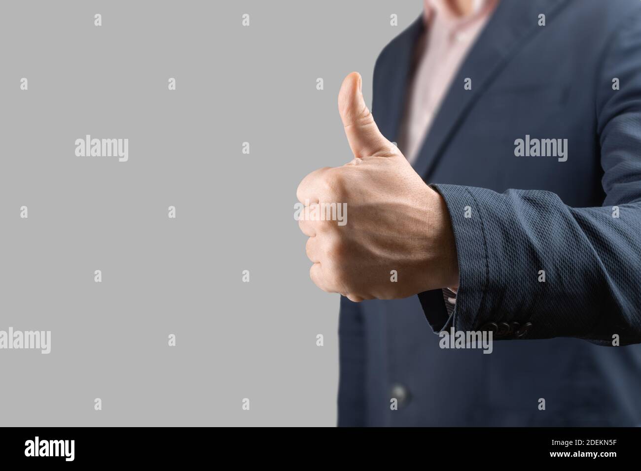 Mano di uomo d'affari che dà pollici su isolato su sfondo grigio. Primo piano gesturing mano OK isolato su bianco. Uomo d'affari con pollice su dorso grigio Foto Stock