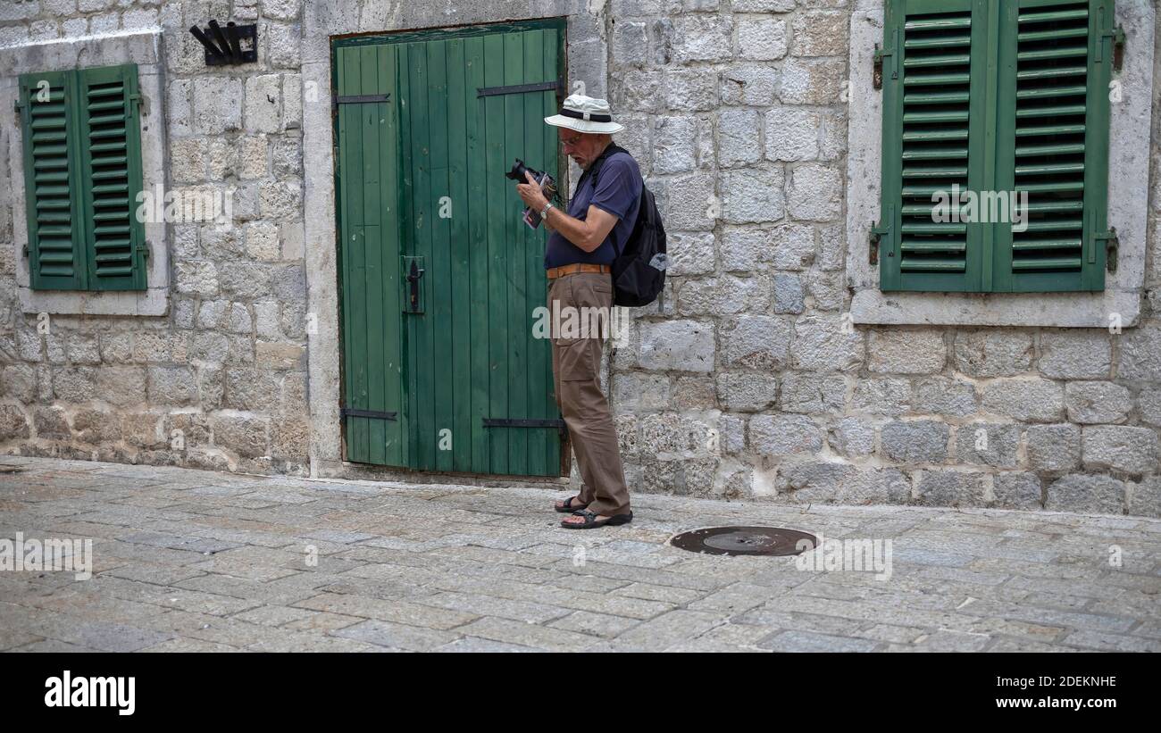 Montenegro, 22 settembre 2019: Un fotografo che regola la sua macchina fotografica per strada della città vecchia di Cattaro Foto Stock