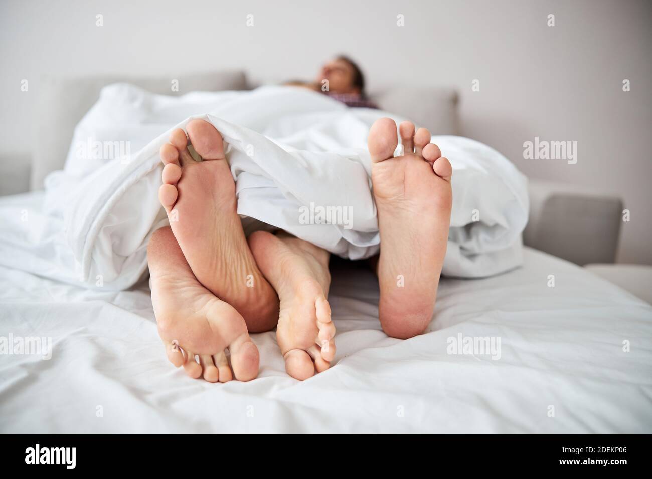 Giovane coppia in amore riposante a letto con gambe intrecciate Foto Stock