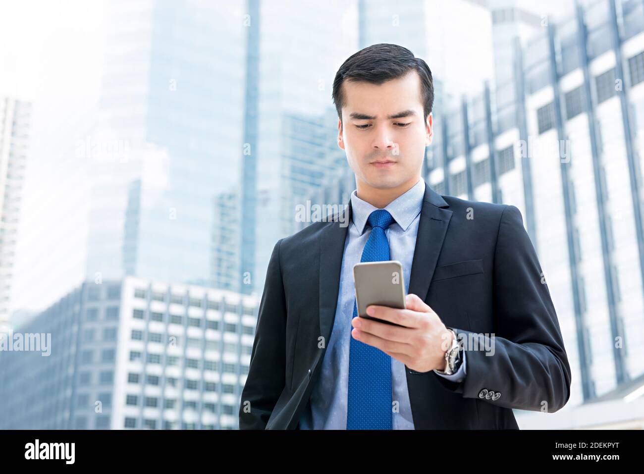 Bell'uomo d'affari in tuta formale guardando lo schermo dello smartphone, controllando le informazioni online mentre si viaggia all'aperto in città - roaming dati mobile Foto Stock