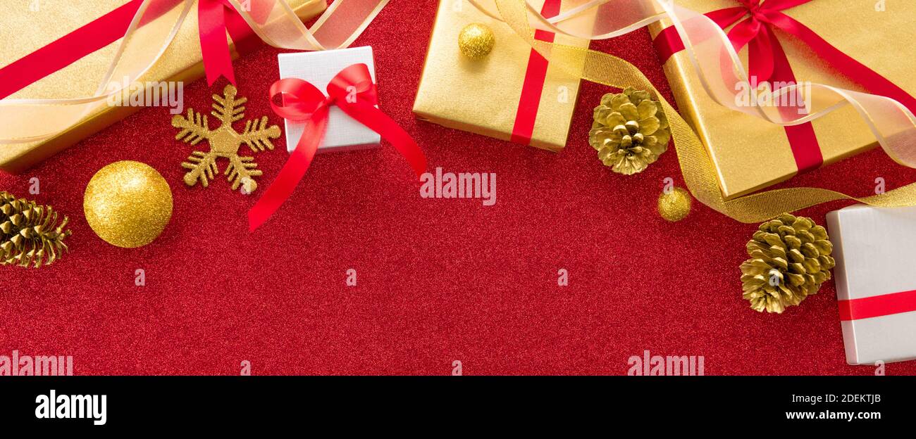 Scatole regalo per Natale e Capodanno lucenti con oggetti decorativi su sfondo colorato rosso velluto scintillante banner - vista dall'alto, bordo design wi Foto Stock