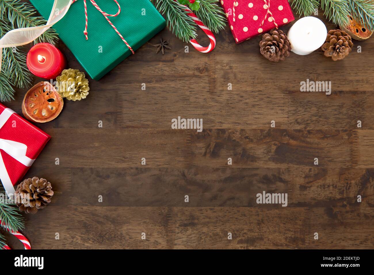 Scatole regalo colorate per le vacanze di Natale su un tavolo di legno marrone scuro con oggetti decorativi, vista dall'alto sullo sfondo del disegno del bordo con spazio di copia Foto Stock