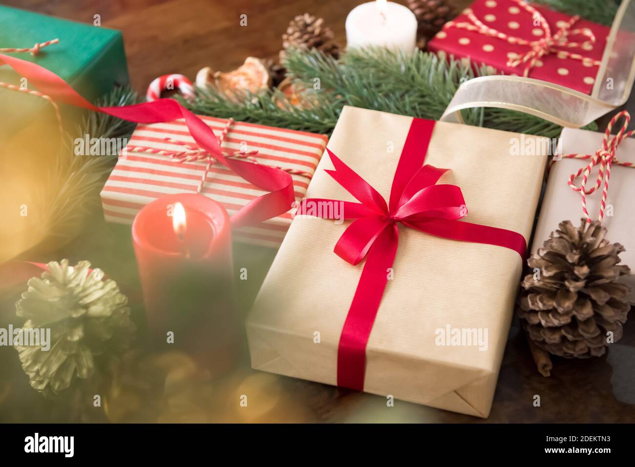 Gruppo di scatole regalo di Natale colorate con candele e decorazione gli articoli nel tavolo a casa preparati per celebrare festa stagione di festa Foto Stock