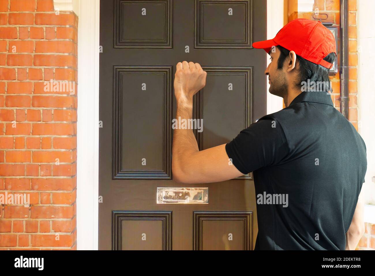 Il responsabile della consegna bussa alla porta per consegnare l'ordine Foto Stock