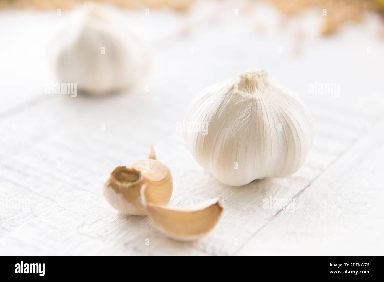 Bella sana aglio bulbi e spicchi di erbe come spezie e. ingrediente di cottura su tavola di legno bianco Foto Stock