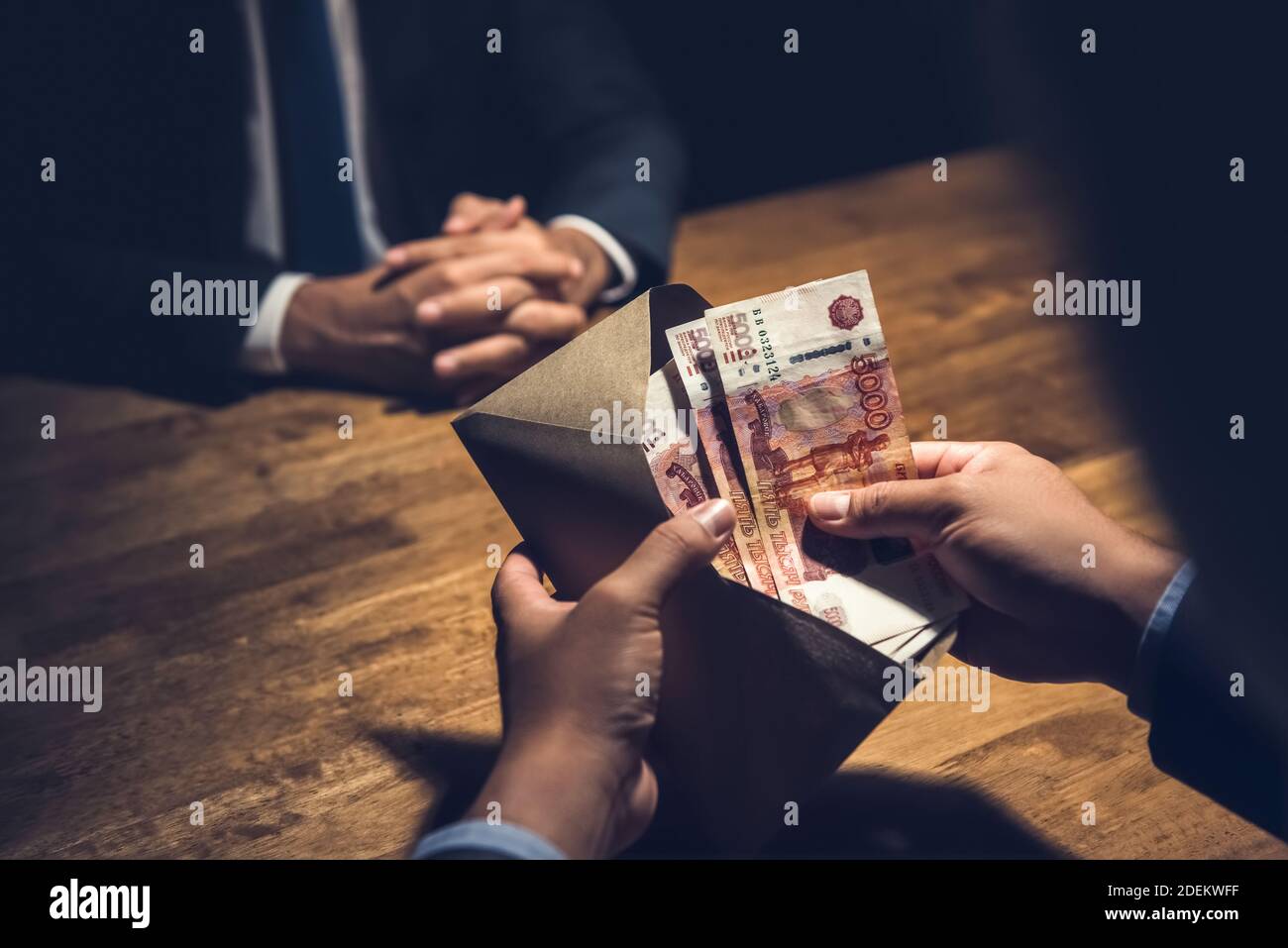 Uomo d'affari che conta rubli russi in busta di denaro marrone come parte di accordo segreto in camera oscura privata Foto Stock