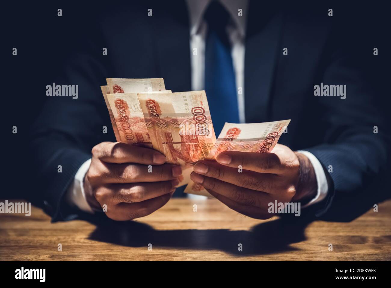 Uomo d'affari che conta denaro, valuta rubla russa, al tavolo in camera privata oscura - concetti di venalità e corruzione Foto Stock