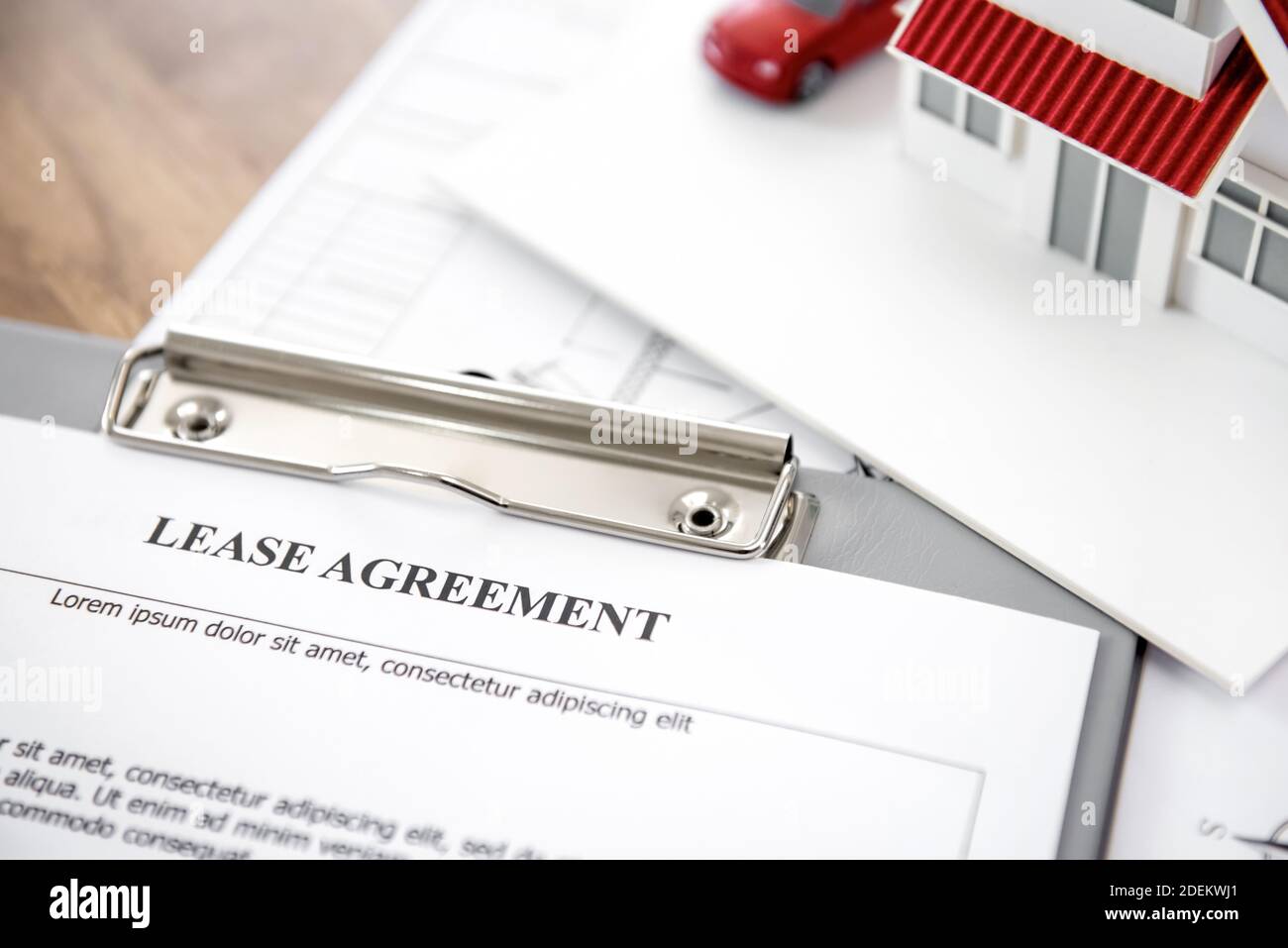 Casa e modello di automobile con carta di contratto di affitto su un appunti al tavolo per un progetto di sviluppo immobiliare Foto Stock