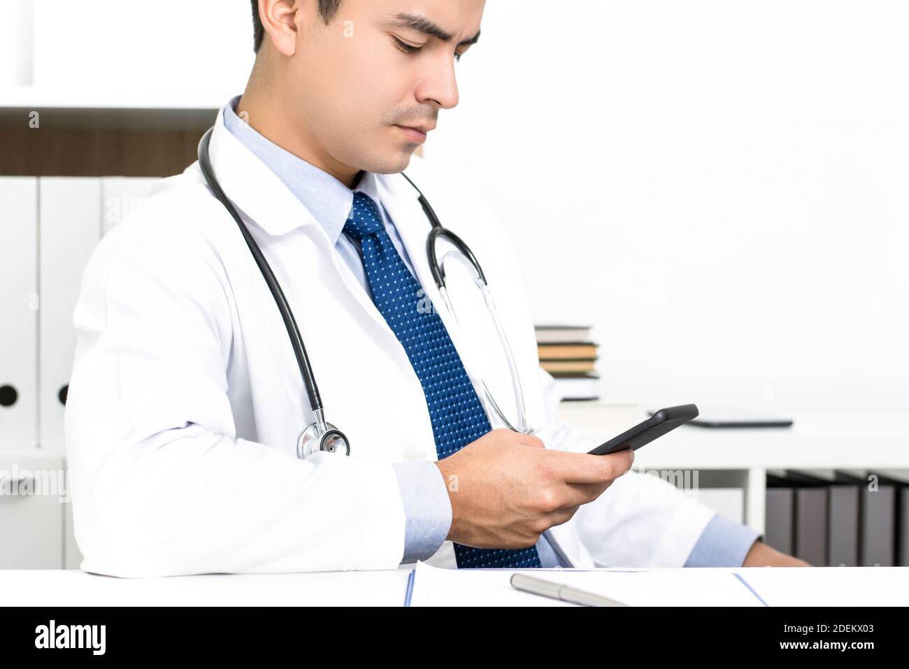 Dottore che si concentra sull'utilizzo della tecnologia per smartphone alla ricerca di informazioni online nella stanza dell'ospedale Foto Stock