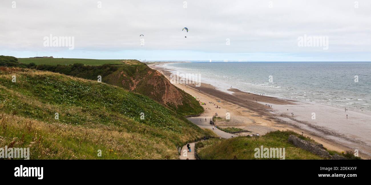 Vista sulla spiaggia di Saltburn Il Mare, Inghilterra, Regno Unito con un parapendio che va lungo la scogliera top Foto Stock