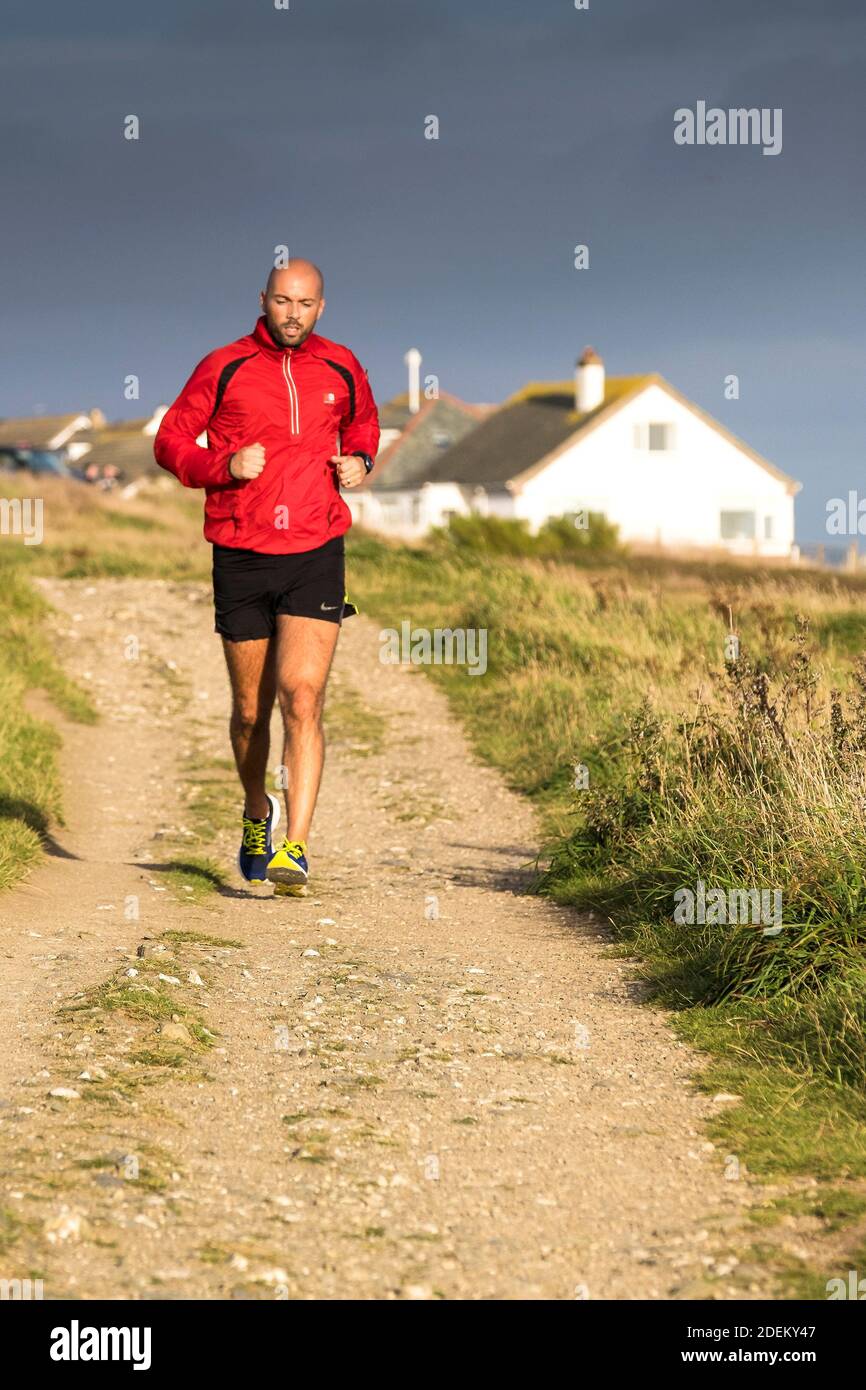 Un uomo che corre lungo un sentiero lungo Pentire Point East a Newquay in Cornovaglia. Foto Stock
