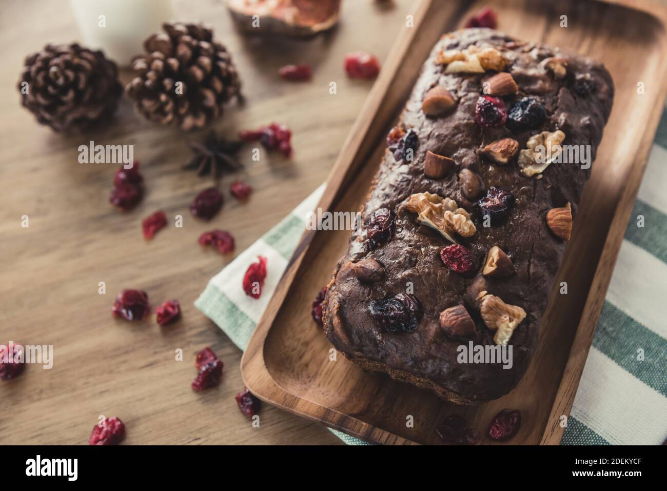 Torta fresca fatta in casa di frutta secca al cioccolato misto con nocciole su un piastra in legno e panno da cucina nella panetteria Foto Stock