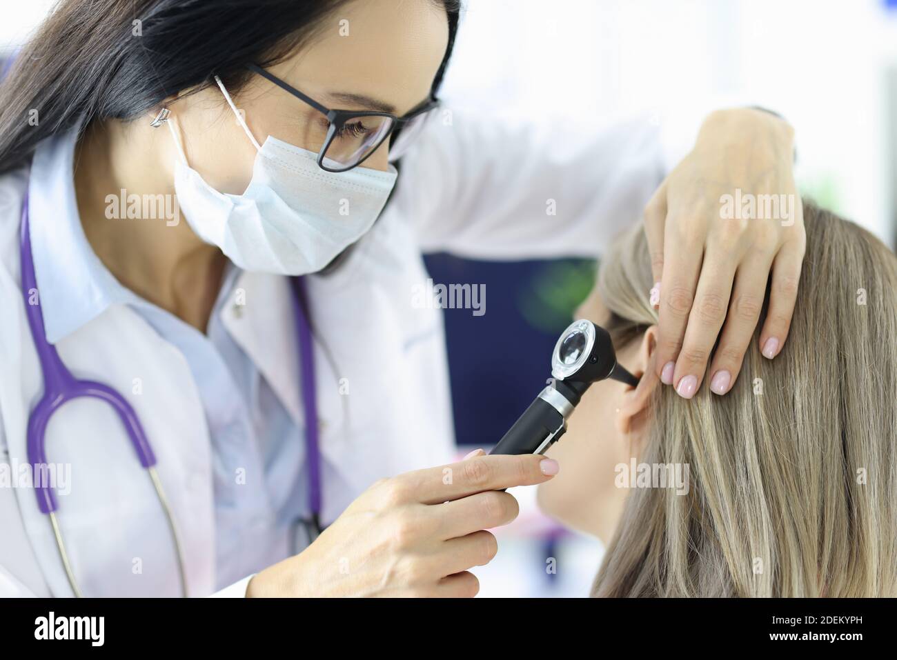 Otorhinolaringologo che guarda i pazienti all'orecchio con otoscopio in clinica Foto Stock