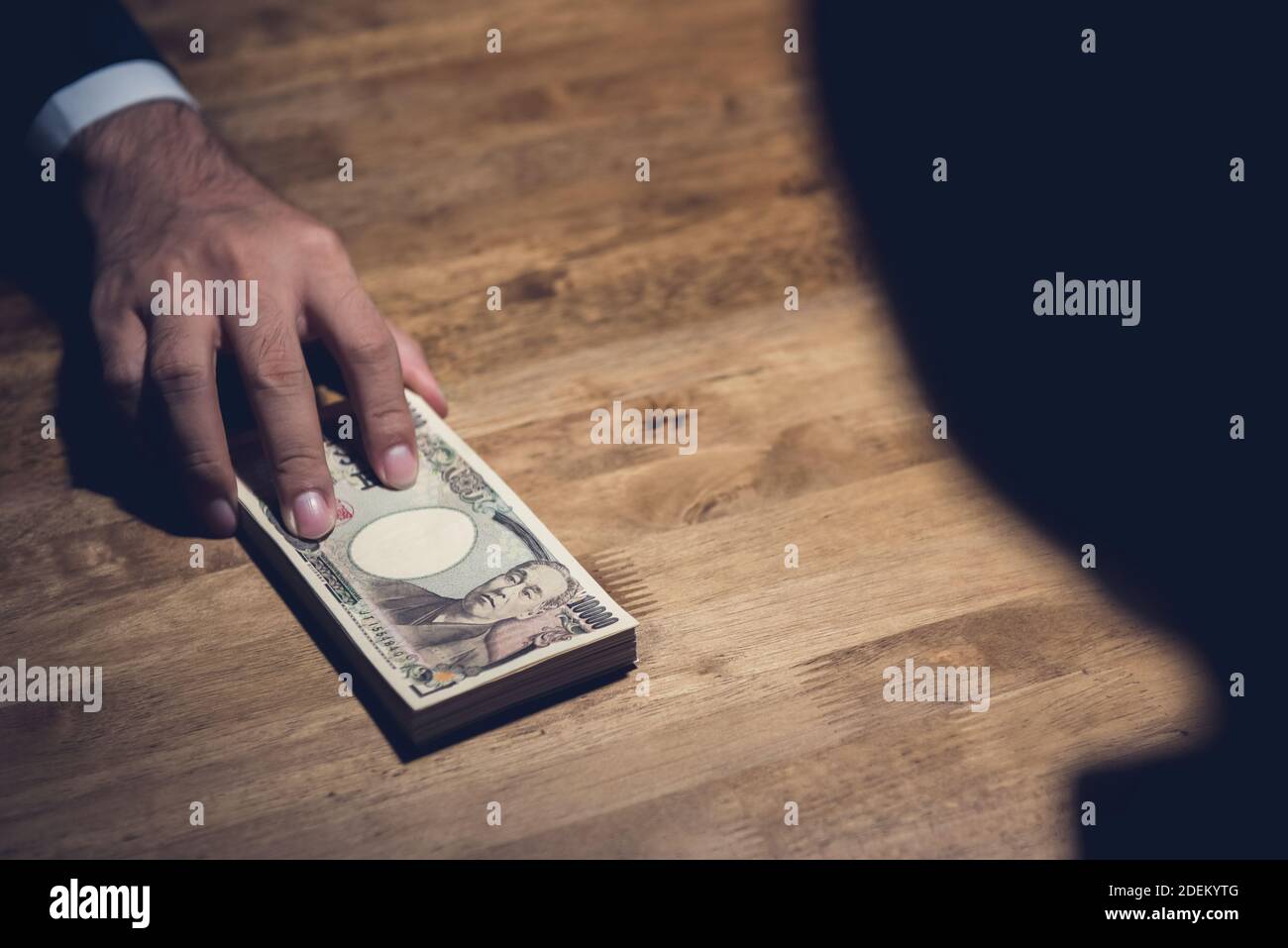 Un uomo d'affari che dà le banconote giapponesi di Yen al suo socio sul tavolo di lavoro in atto di corruzione in privacy e segretezza Foto Stock
