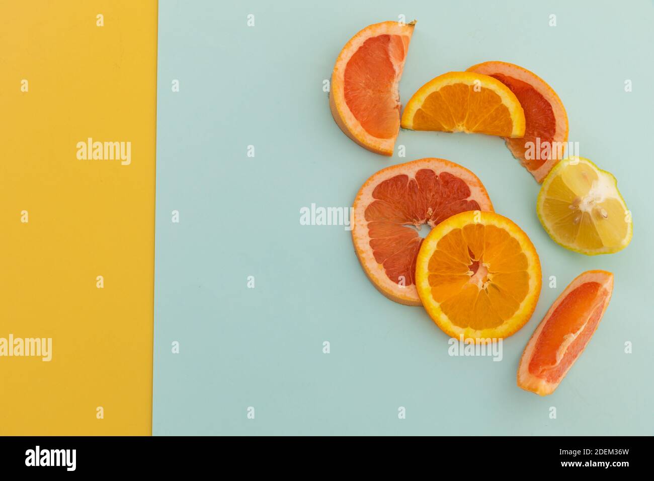Fette di pompelmo, arancio e limone su fondo blu e giallo Foto Stock