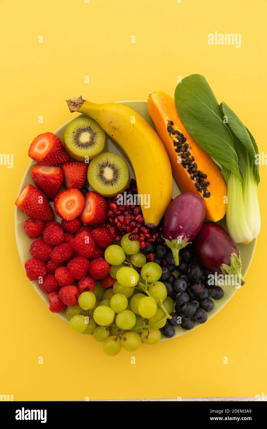 Vista ad alto angolo della ciotola di banana, bacche, uva e melanzane Foto Stock