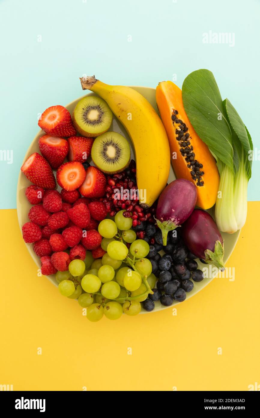Vista ad alto angolo della ciotola di banana, bacche, uva e melanzane Foto Stock