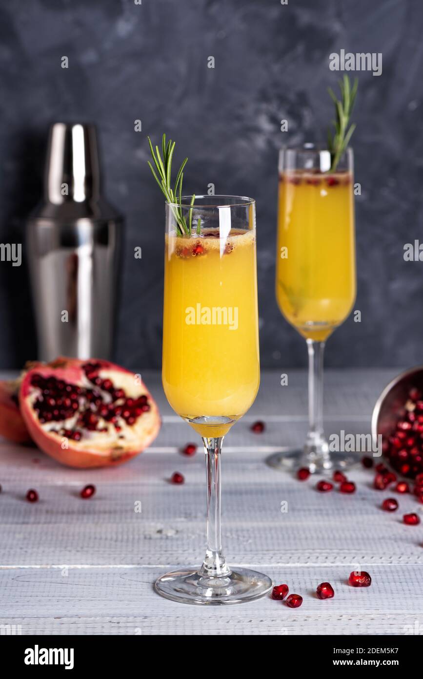 Cocktail Mimosa con succo d'arancia e champagne. Festa di Capodanno o di compleanno. Melograno e rosmarino Foto Stock