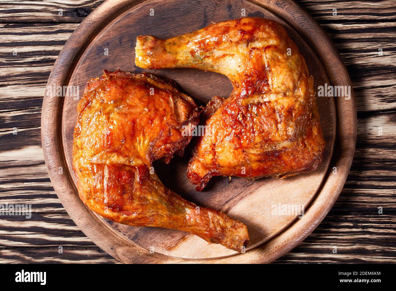 Quarti di coscia di pollo, cotti al forno, pelle-sopra, osso-in, serviti su sfondo di legno, vista dall'alto, primo piano Foto Stock