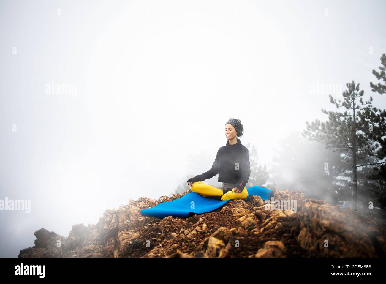 Donna che medita e pratica yoga in cima alla montagna Foto Stock
