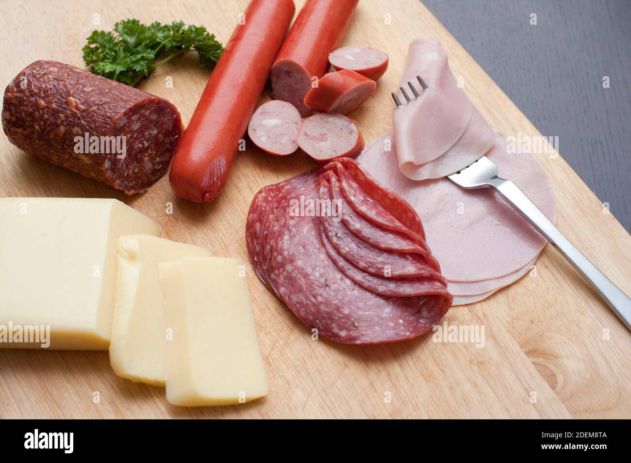 Ricca colazione tradizionale tedesca con salumi assortiti, salumi e carni fredde, accompagnati da fette di formaggio servite su un trito di legno Foto Stock