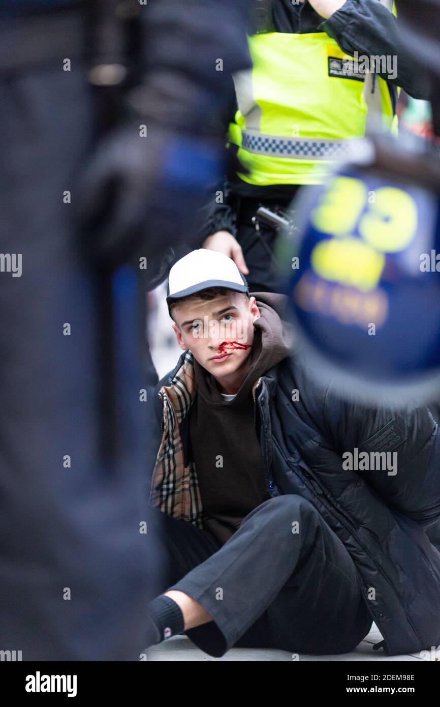 Protesta anti-lock-down, Oxford Street, Londra, 28 novembre 2020. Un protestante arrestato con sangue siede sul marciapiede circondato dalla polizia. Foto Stock