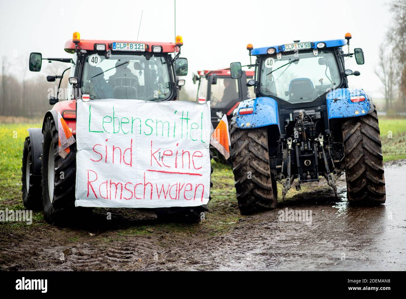 Cloppenburg, Germania. 01 dicembre 2020. Un trattore, al quale è apposta una bandiera con la scritta "Lebensmittel sind keine Ramschwaren", blocca l'accesso al magazzino centrale di Lidl. Centinaia di agricoltori hanno continuato a protestare contro la politica dei prezzi del commercio al dettaglio di prodotti alimentari nella notte del 01.12.2020. Credit: Hauke-Christian Dittrich/dpa/Alamy Live News Foto Stock