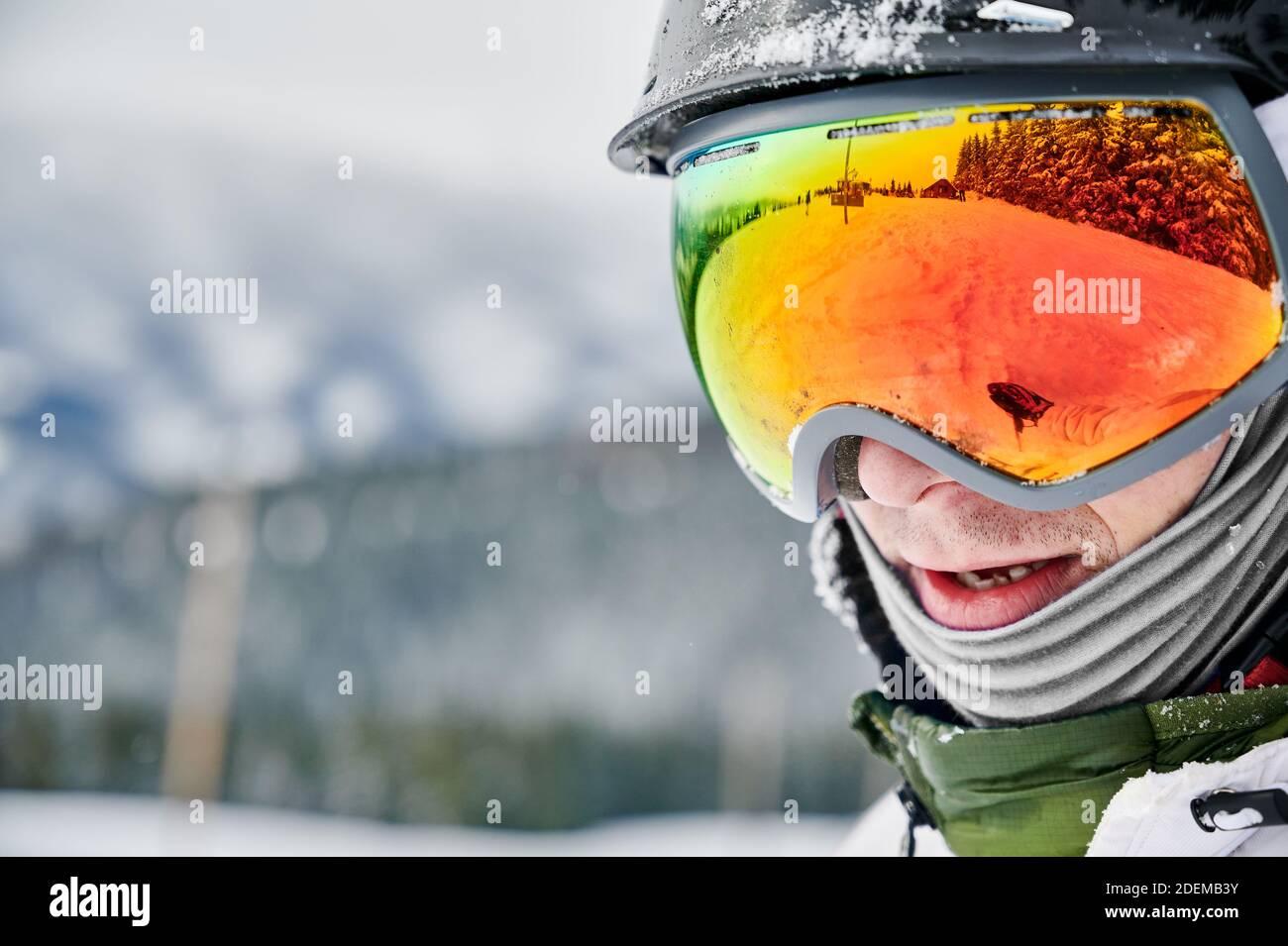 Primo piano immagine ritagliata di un uomo che indossa occhiali da sci con riflesso della pista innevata. Occhiali luminosi che riflettono la natura in inverno. Concetto di stile di vita attivo Foto Stock