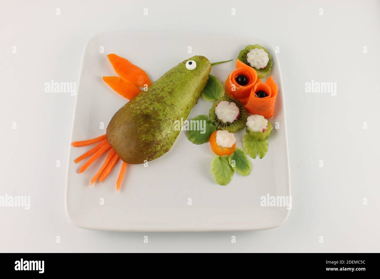 Piatto colorato di cibo vegano fatto sembrare un uccello humming su fiori, isolato su uno sfondo bianco con spazio copia Foto Stock