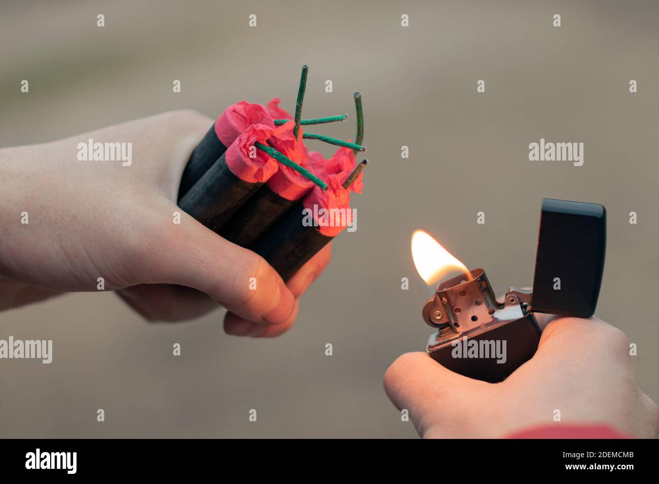 Uomo che illumina diversi Firecrackers in mano con accendino a benzina. Guy prepararsi per il divertimento di Capodanno con fuochi d'artificio o prodotti pirotecnici - primo piano, vista posteriore Foto Stock