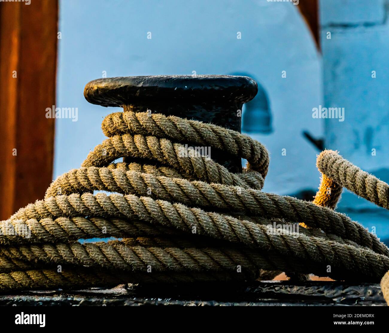 Ormeggi di corda di canapa marittima su un bollard di ghisa nera sul molo. . Foto di alta qualità Foto Stock