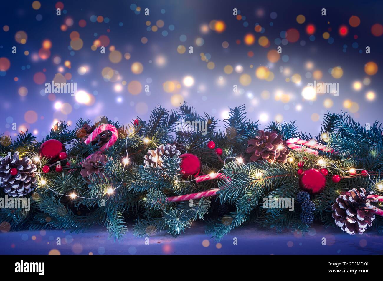Natale Garland con luci luminose su uno sfondo sfocato di luci notturne scure. Foto Stock