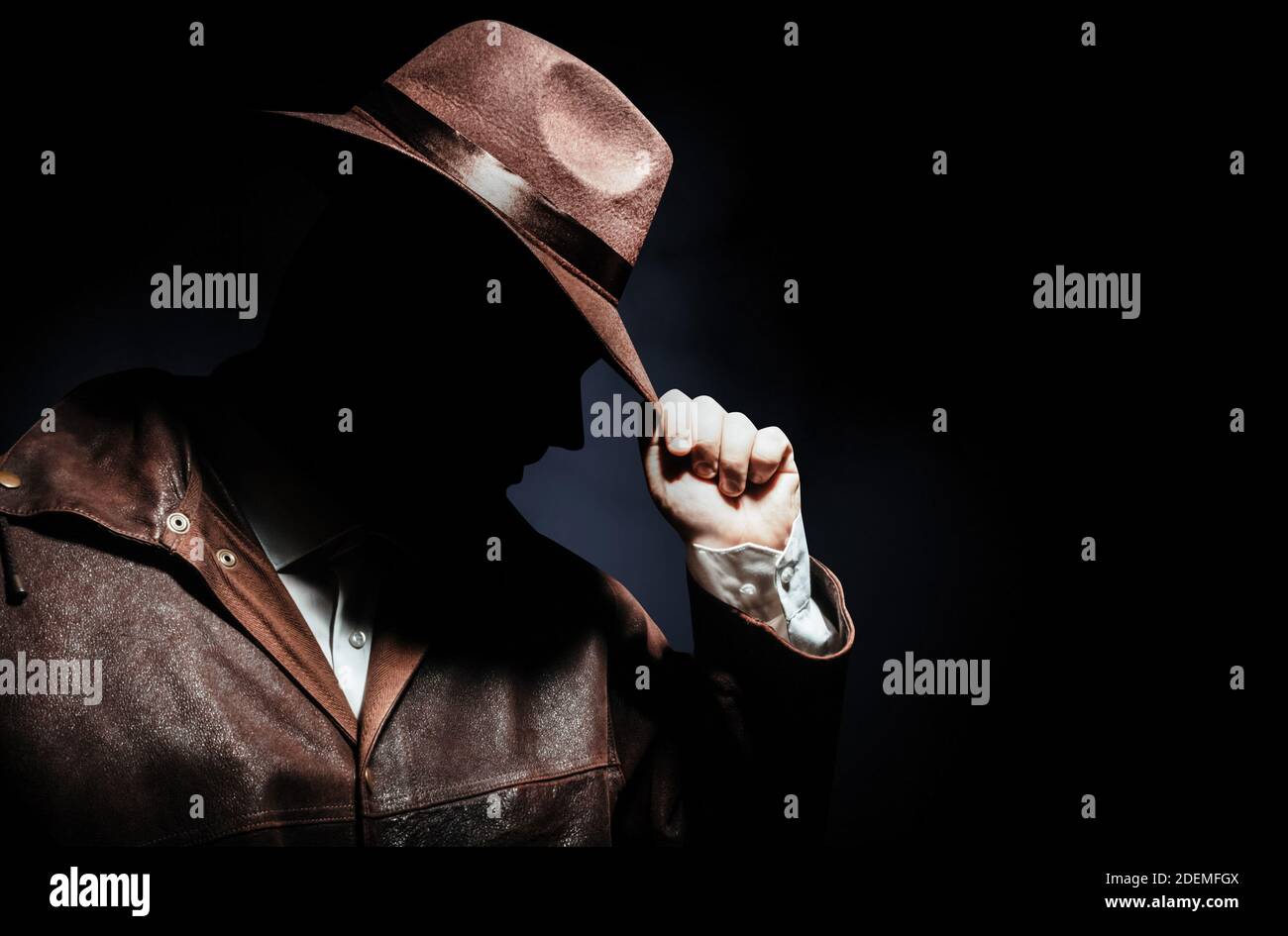 Foto di un ritratto detective ombreggiato in giacca che indossa il cappello  su sfondo nero Foto stock - Alamy
