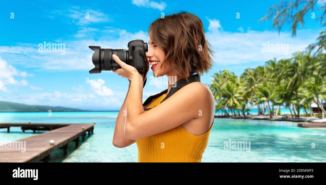 felice fotografo donna con macchina fotografica sulla spiaggia Foto Stock