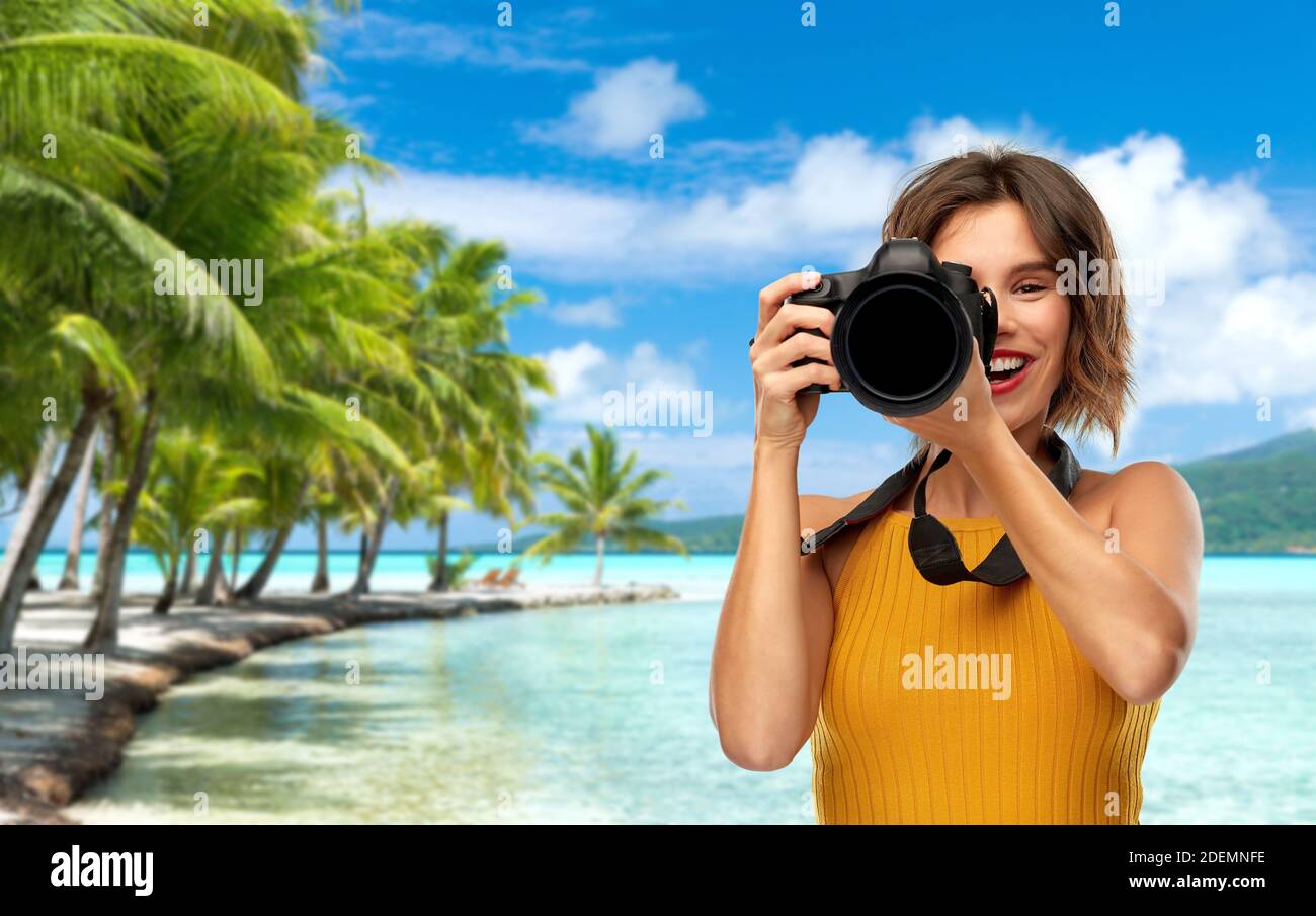 felice fotografo donna con macchina fotografica sulla spiaggia Foto Stock
