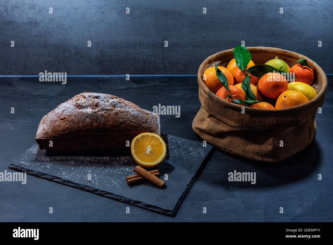 Torta agli agrumi biologica accanto a un cestino di agrumi biologici. Foto Stock