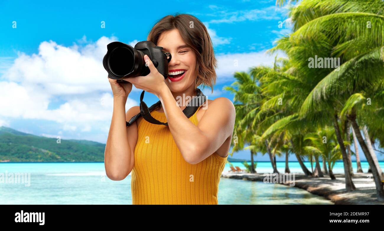 felice fotografo donna con macchina fotografica sulla spiaggia Foto Stock