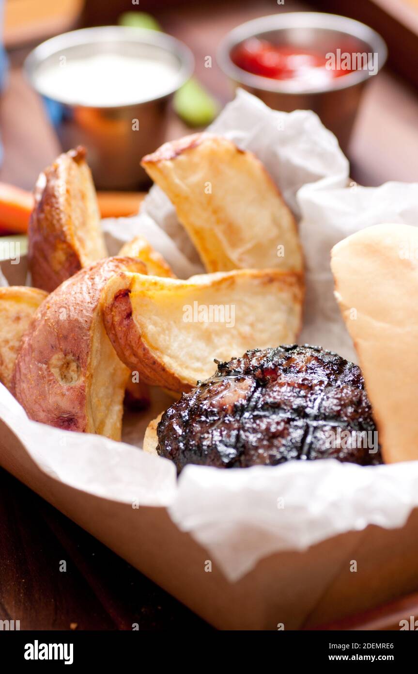 hamburger di maiale rialzato con spicchi di patate rosse tagliati a mano e bastoncini di verdure prendere fuori stock foto Foto Stock