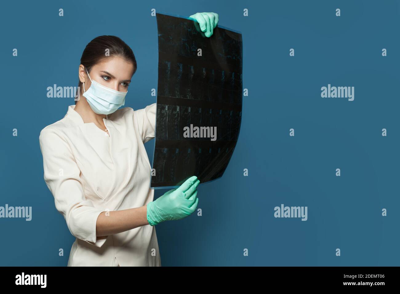 Medico in maschera medica protettiva che tiene la tomografia computerizzata scansione on sfondo blu Foto Stock