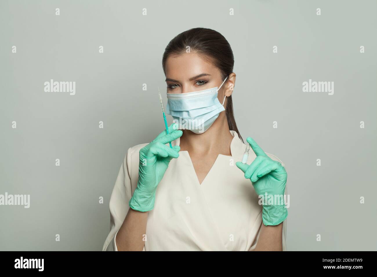 Felice ottimista dottore o infermiera donna in uniforme professionale che tiene siringa e ampolla su sfondo bianco. Medicina, cosmetologia e vaccinazione Foto Stock