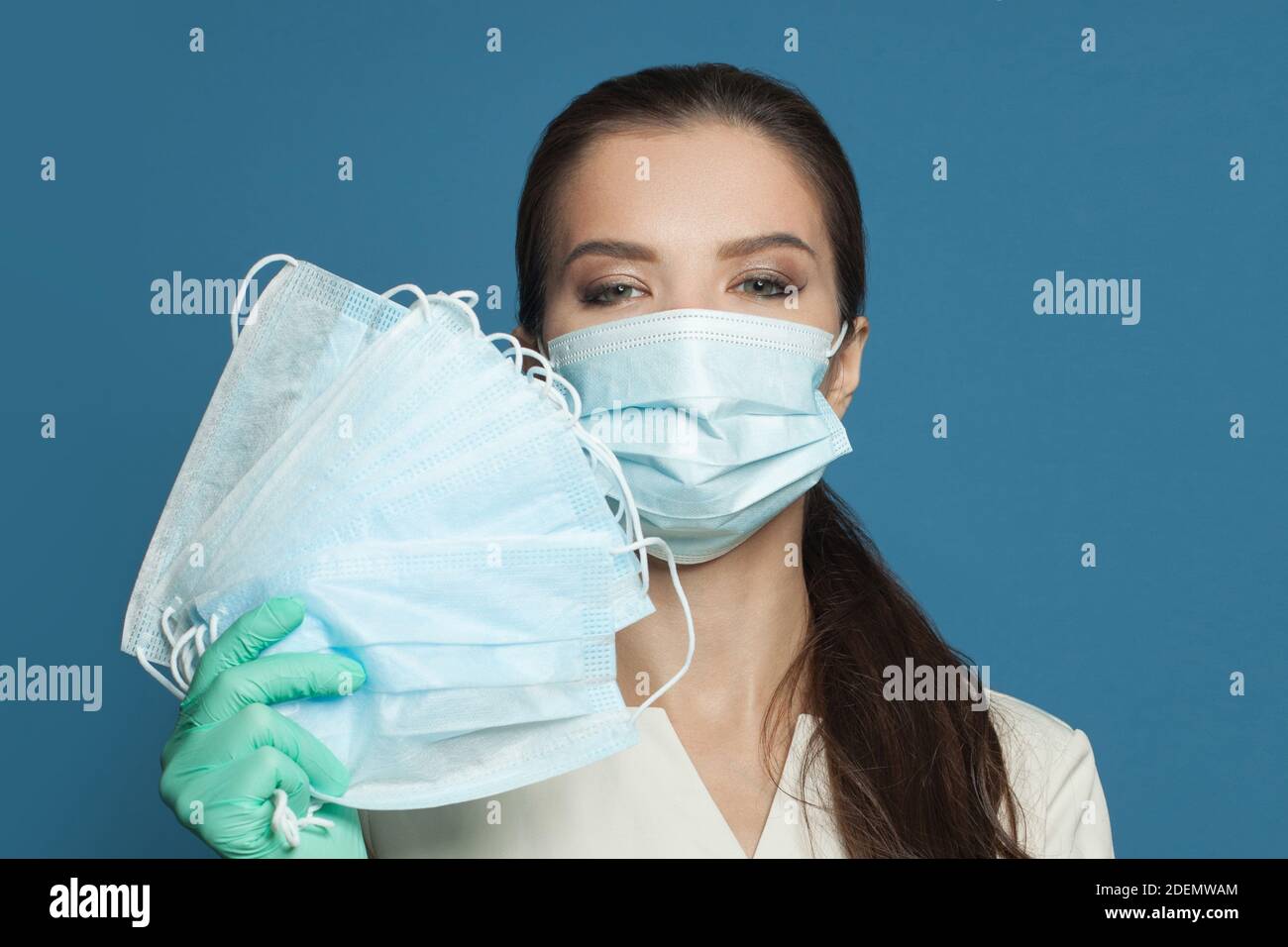 Felice dottore donna che tiene molte maschere mediche protettive. Medicina, cosmetologia e concetto di sicurezza Foto Stock