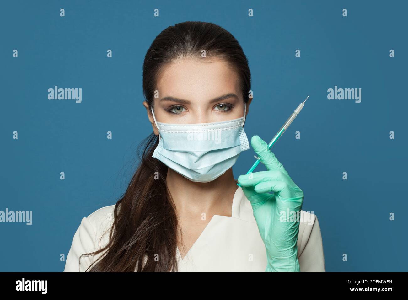 Ritratto di donna dottore o infermiera in uniforme professionale con siringa in mano su sfondo blu. Medicina, cosmetologia e concetto di vaccinazione Foto Stock