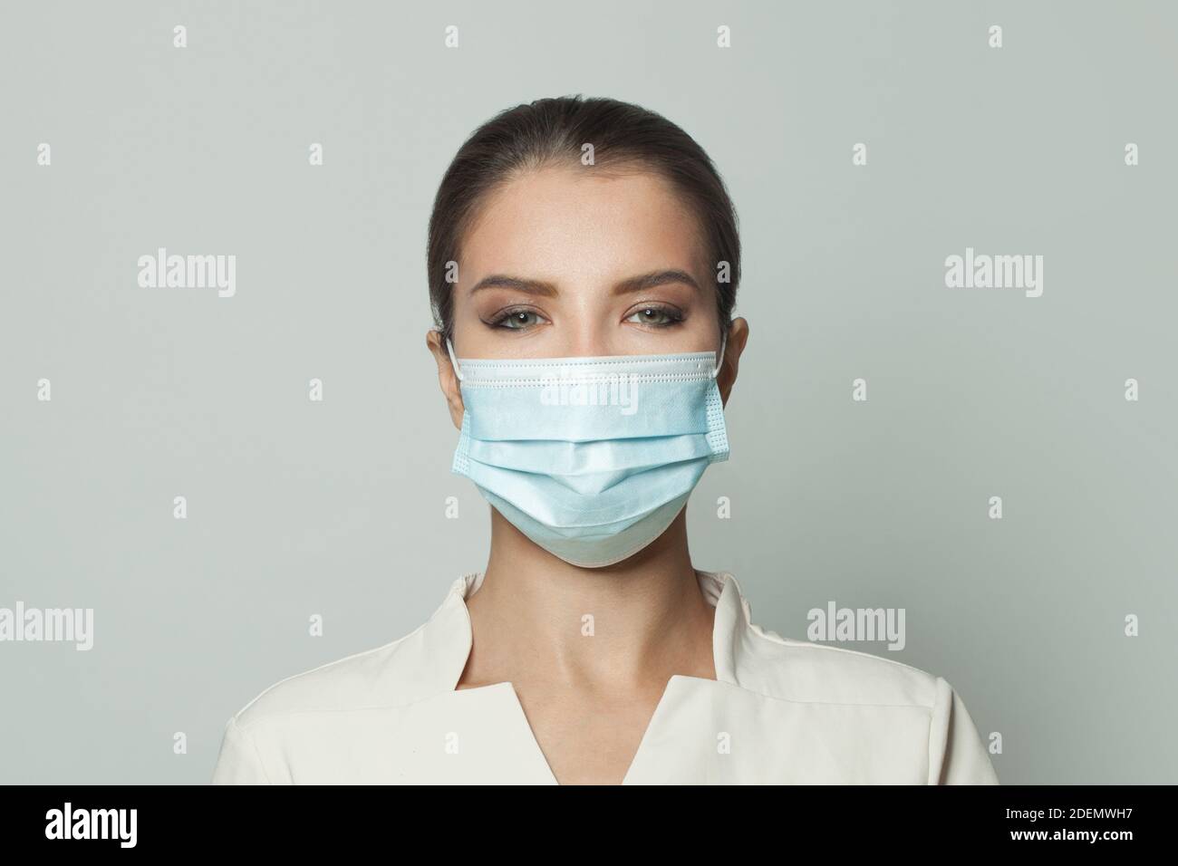 Ritratto di donna che indossa una maschera medica protettiva su sfondo bianco. Medicina, cosmetologia e concetto di vaccinazione Foto Stock