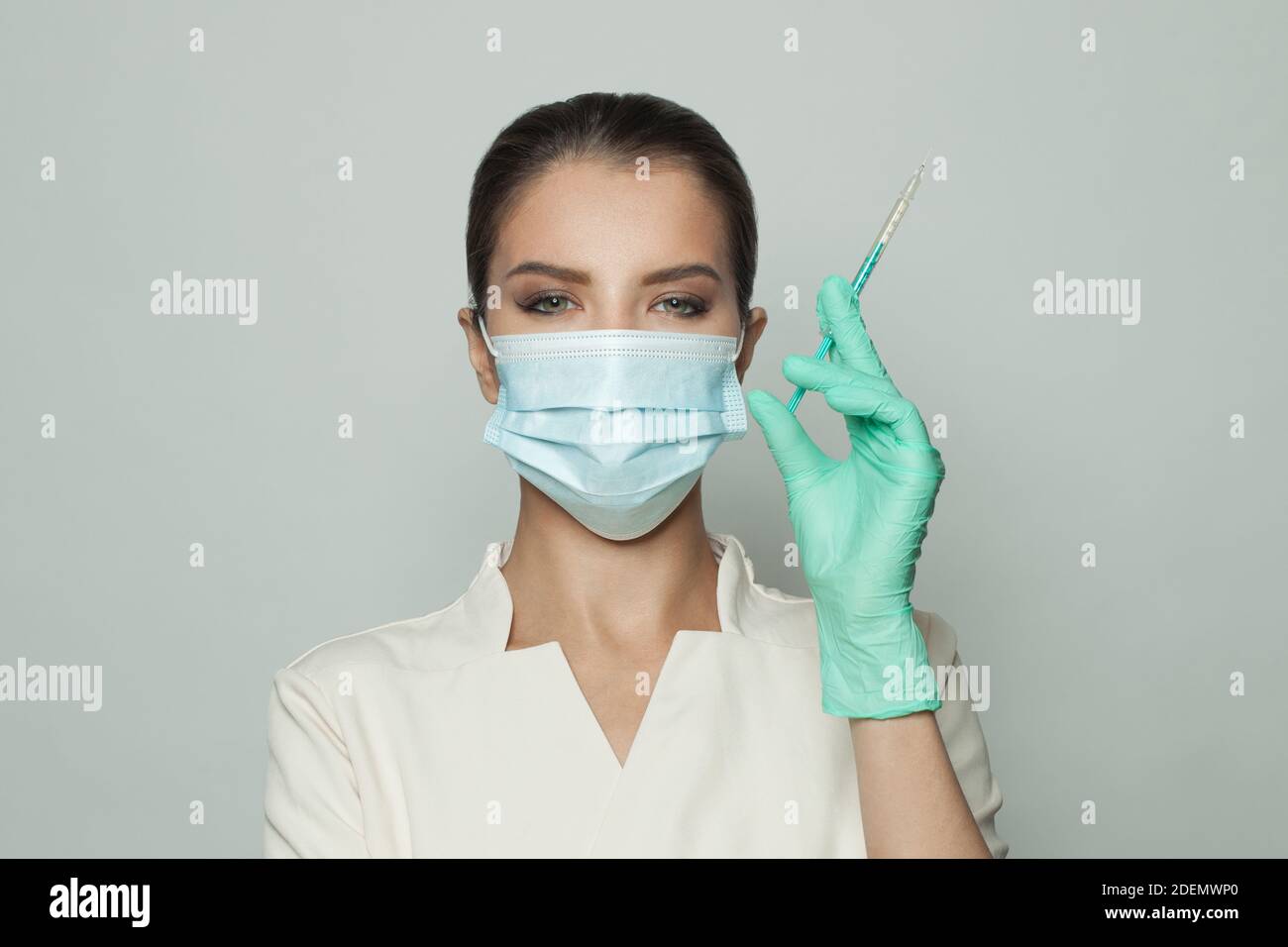 Ritratto di dottore che indossa una siringa professionale che tiene in mano su sfondo bianco. Medicina, cosmetologia e concetto di vaccinazione Foto Stock